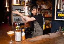 A bearded barman shakes up a cocktail