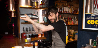 A bearded barman shakes up a cocktail