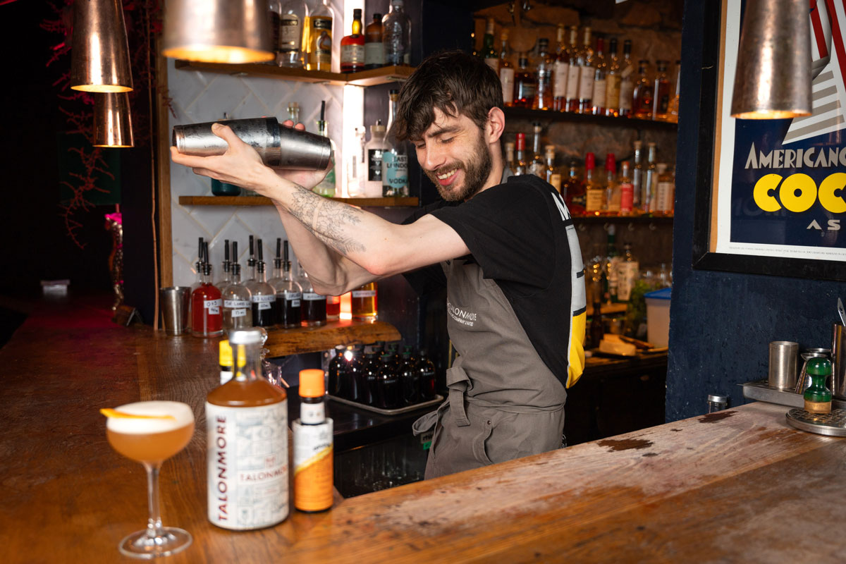 A bearded barman shakes up a cocktail