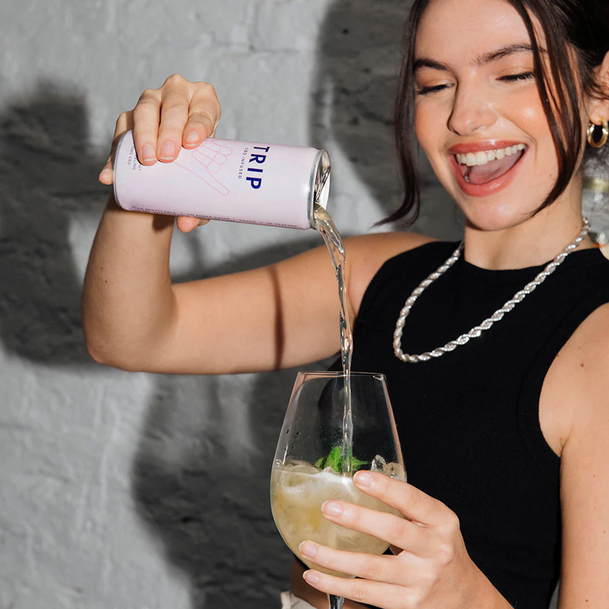 A happy lady pours a can of drink into a glass