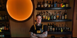 A heavily tattooed bar person in their place of work