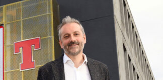 A businessman stands in front of a beer brand logo