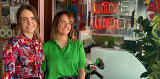 Two restaurant staff stand at a brightly decorated venue entrance