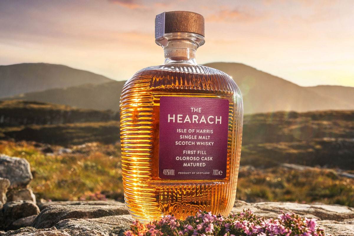 A single whisky bottle sits in the Scottish landscape