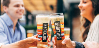 Two glasses of cider are clinked over a table