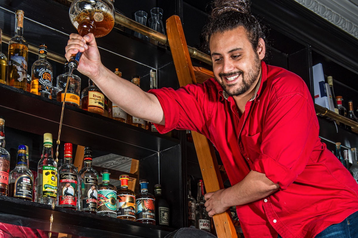 Two bearded bartenders get up to japes with ladders and bottles