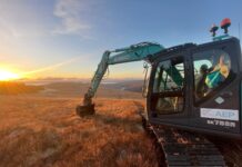 A tracked ground excavator on Scottish moorland in the sunshine.