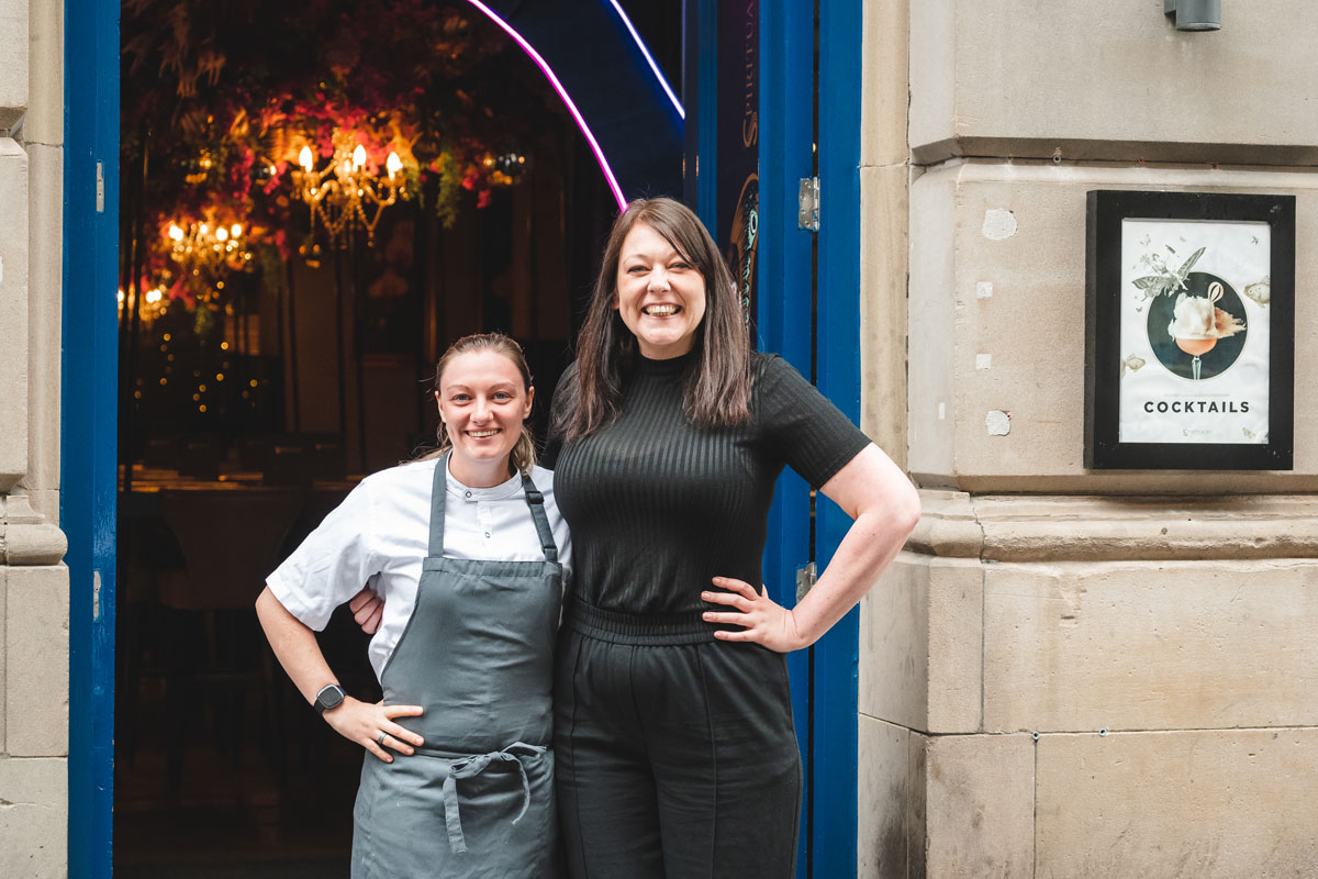 A manageress and a chef stand smiling outside an upmarket venue