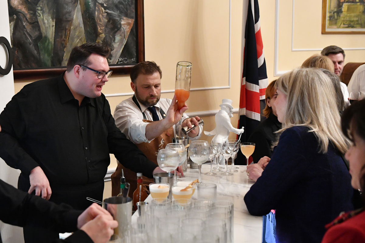 A mixture of people serve and receive drinks.