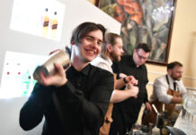 A young person happily uses a cocktail shaker