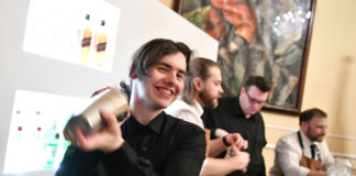 A young person happily uses a cocktail shaker