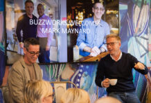 Two middle-aged bespectacled men speak in front of an audience