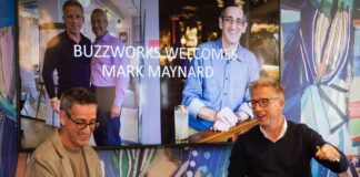 Two middle-aged bespectacled men speak in front of an audience