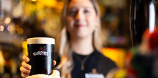 A pint of stout is handed to a customer in a bar