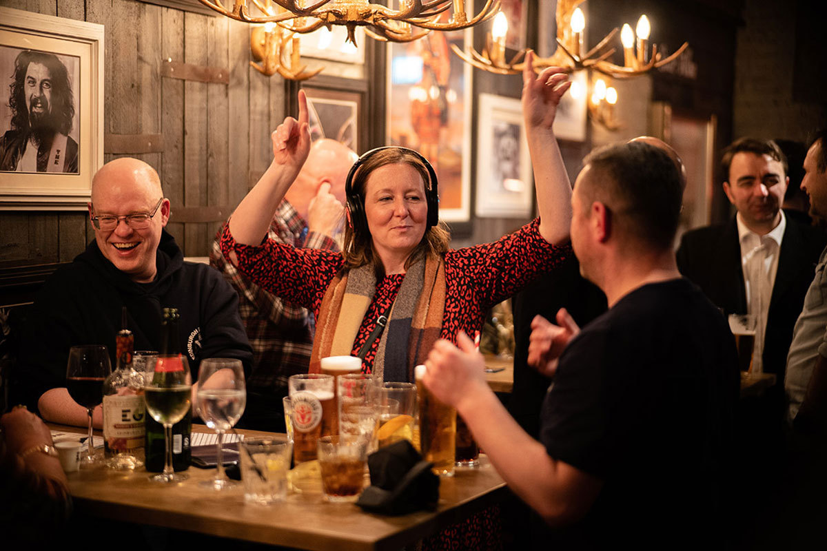 There people sit at a pub table looking jolly