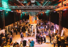 A warehouse style event space full of people and trade stands