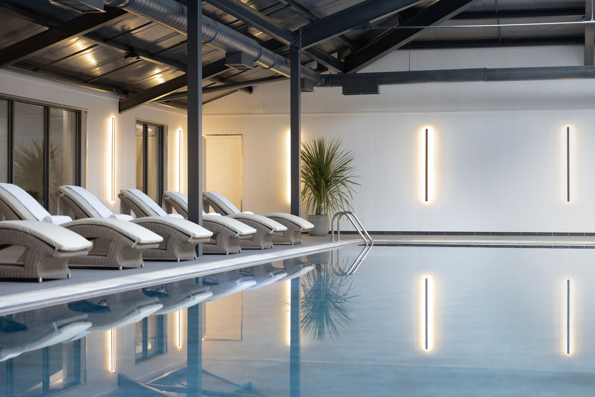 A bright modern luxury swimming pool with loungers alongside
