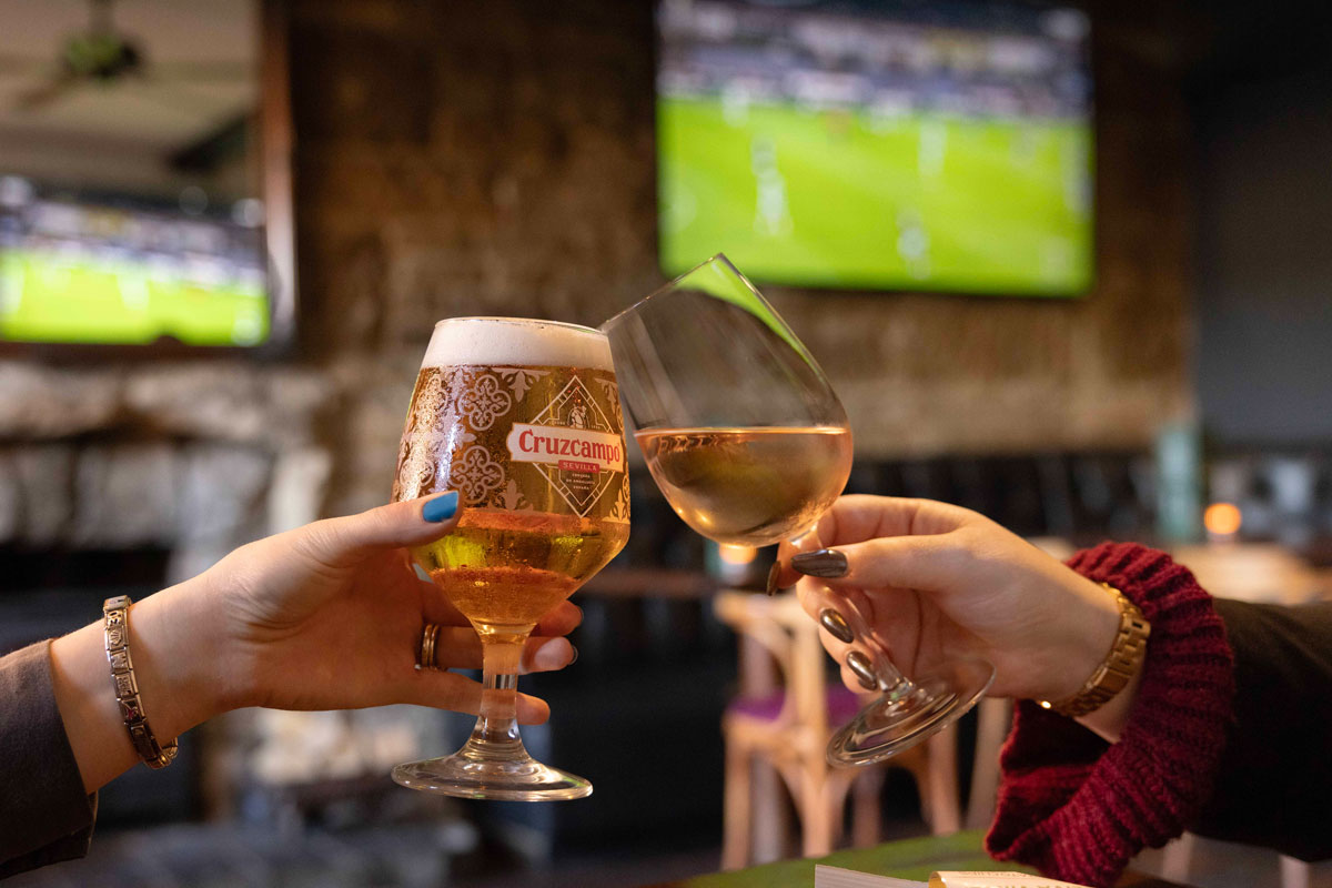Glasses are clinked together in a classic pub setting