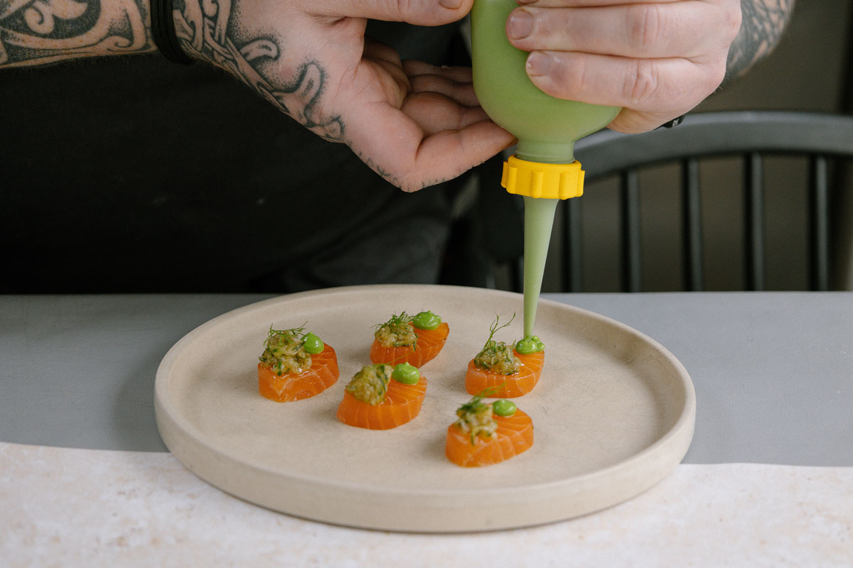 A chef dresses a plate of seafood