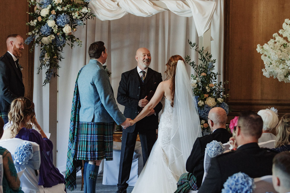 A couple stand at a wedding altar facing a wedding official