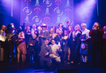 A stage full of well dressed young people celebrate