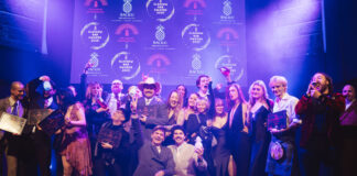 A stage full of well dressed young people celebrate