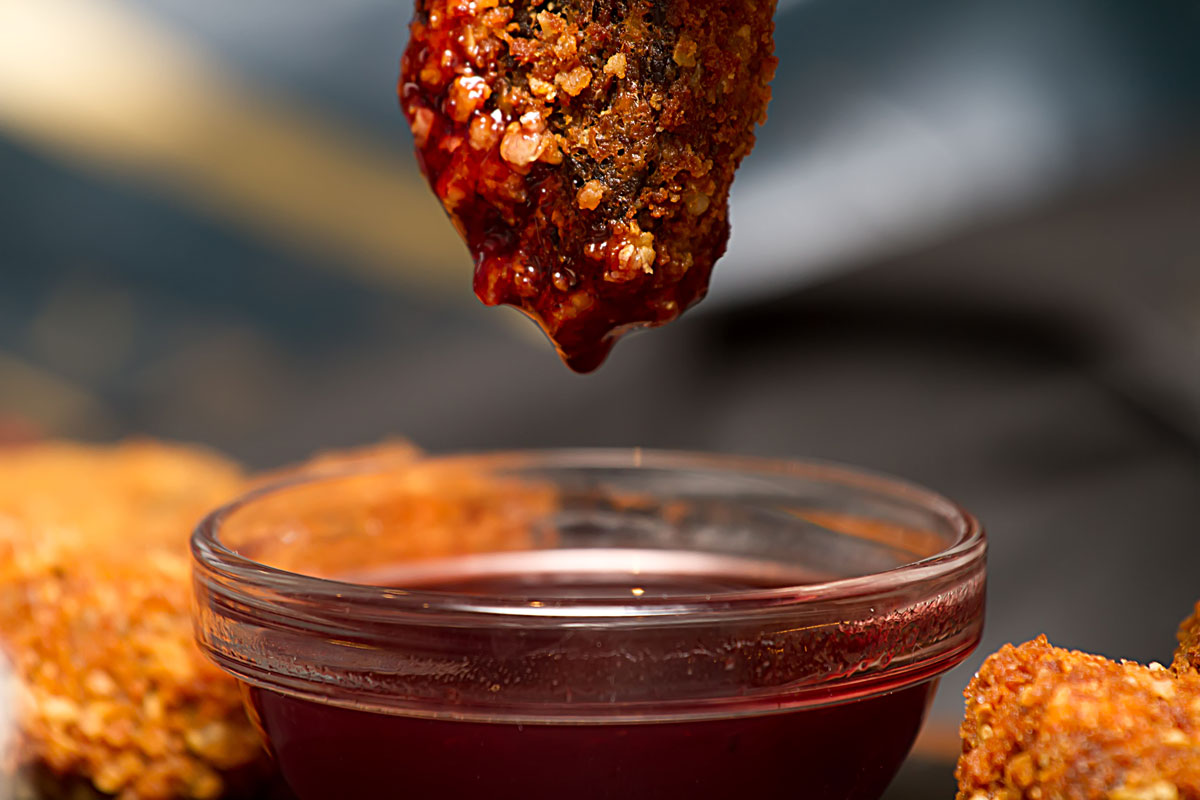 A breaded snack gets dipped in red sauce