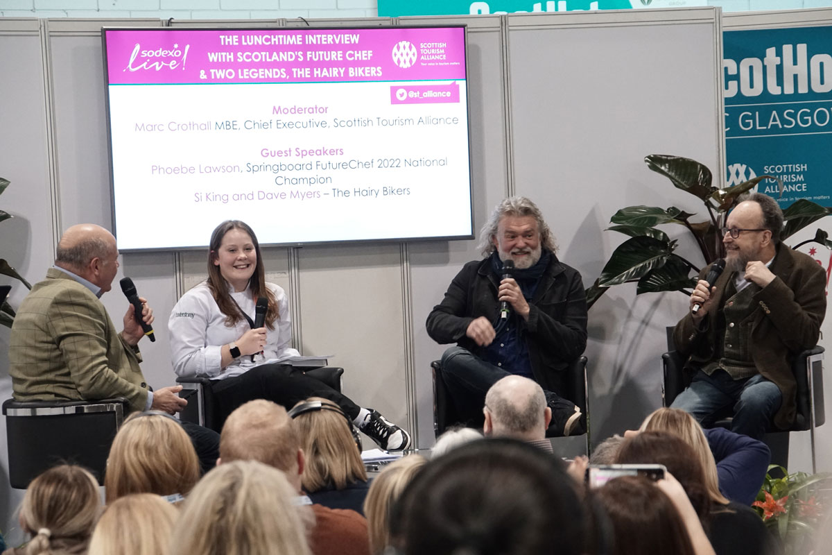 A panel sit on stage at an industry event