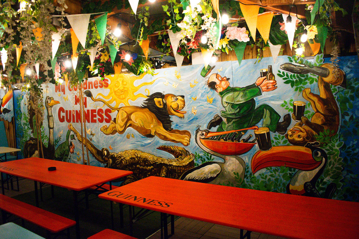 A vintage advertising mural of a lion chasing a man to steal his beer