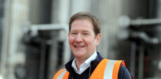 a smiling man wear hi-vis against an industrial background