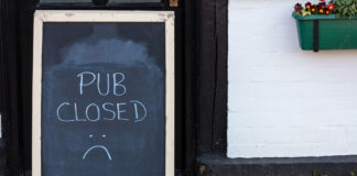 A 'pub closed' billboard on a pavement