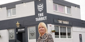 A woman stands outside a black-and white painted pub