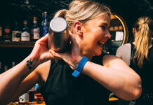 A laughing blonde woman shakes a cocktail