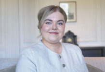 A young woman in a smart suit smiles at the camera