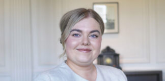 A young woman in a smart suit smiles at the camera