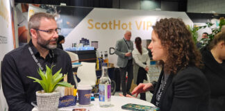 A young woman sits at a round table talking with a heavily bearded man