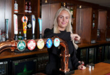A young woman behind a pub bar
