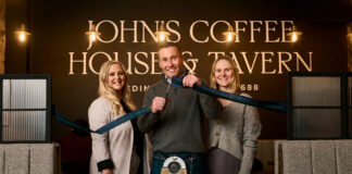 A man cuts a ribbon to open a new building, flanked by a woman on each side