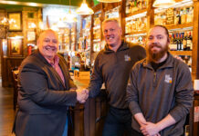 Three men stand smiling in a newly renovated traditional bar