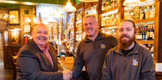Three men stand smiling in a newly renovated traditional bar