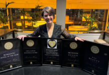 A young woman poses with five framed awards