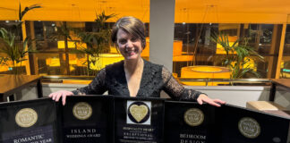 A young woman poses with five framed awards
