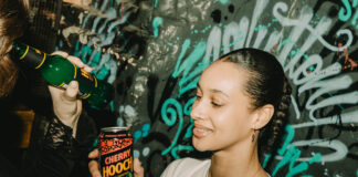A young woman holds up a brightly coloured drinks can