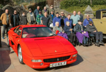A bright red sports car in the foreground, with people all around, some of them in wheelchairs