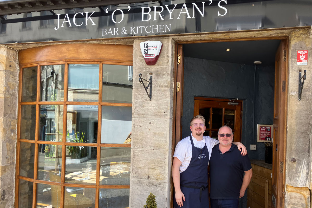 a father and son stand in the doorway of the family restaurant