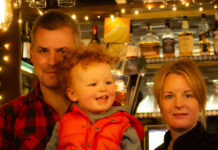 A mother, father and baby son in a warmly lit bar
