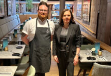 a man in chef's garb stands next to a restaurant manageress