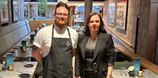 a man in chef's garb stands next to a restaurant manageress