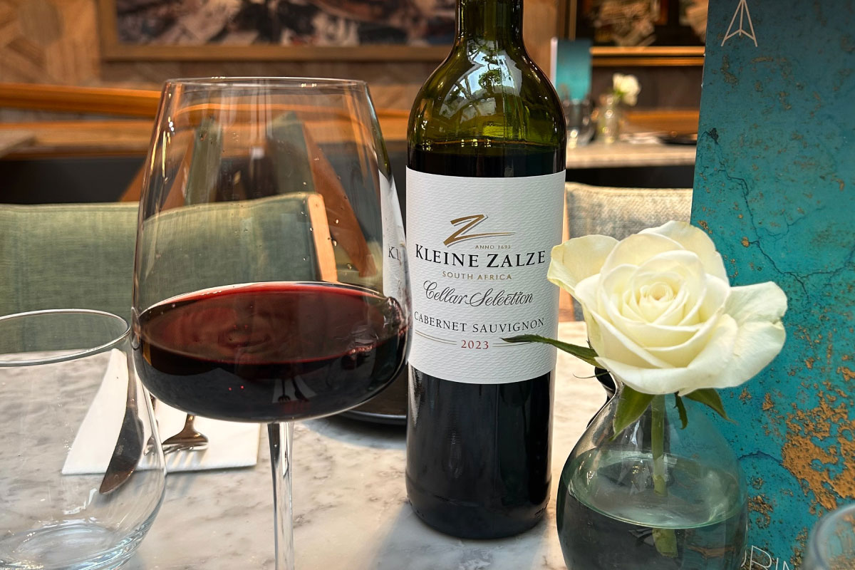 An open bottle of red wine alongside a filled glass