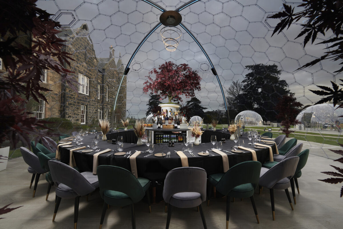 A circular table set for dinner inside a transparent dome